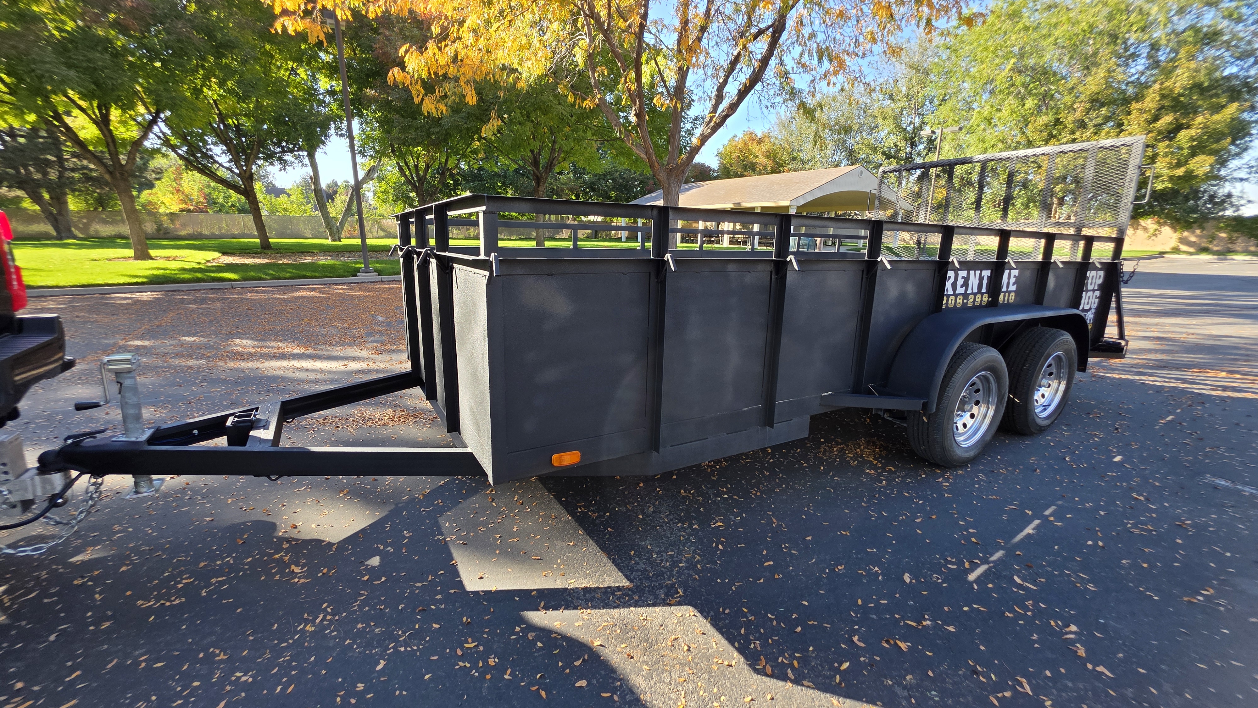 Black Top Dog tandem-axle utility trailer with high steel sides and a mesh rear ramp gate
